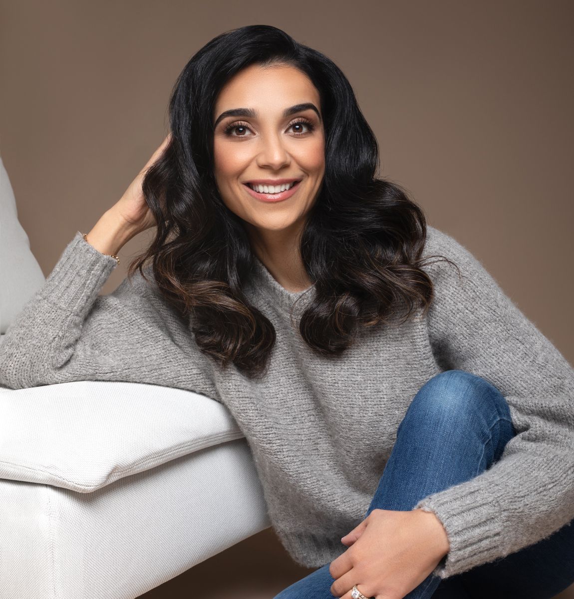 Smiling woman in cozy sweater and jeans.